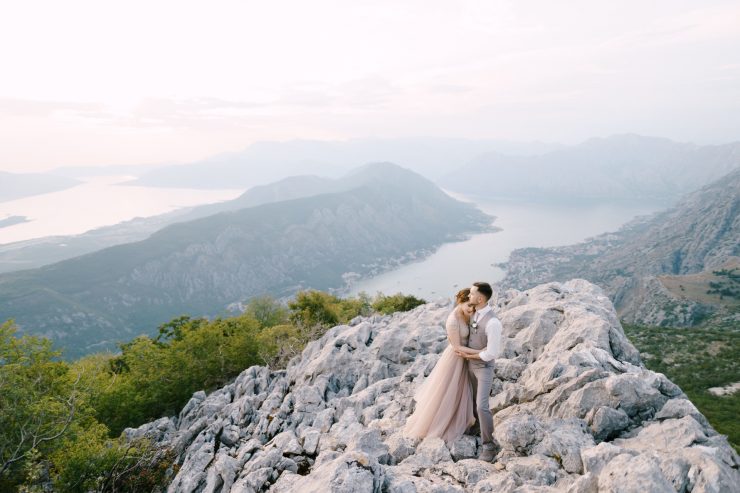 Groom embraces bride on the mountain against the background of the Kotor Bay Drone