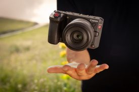 D227 Lifestyle, small and lightweight with 35mm RF f1 8 IS macro, camera mid air above a male hand